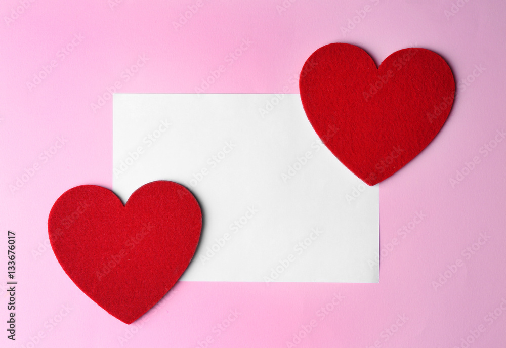 Paper greeting card and decorative hearts on pink background
