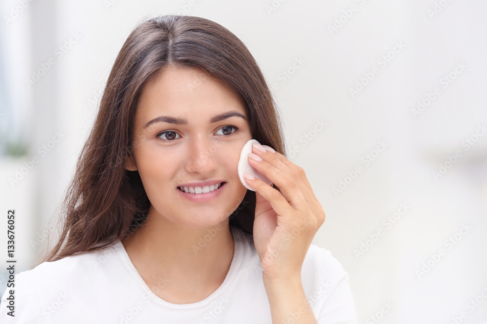 Beautiful girl cleaning face with sponge in front of mirror Beautiful girl cleaning face with sponge in front of mirror