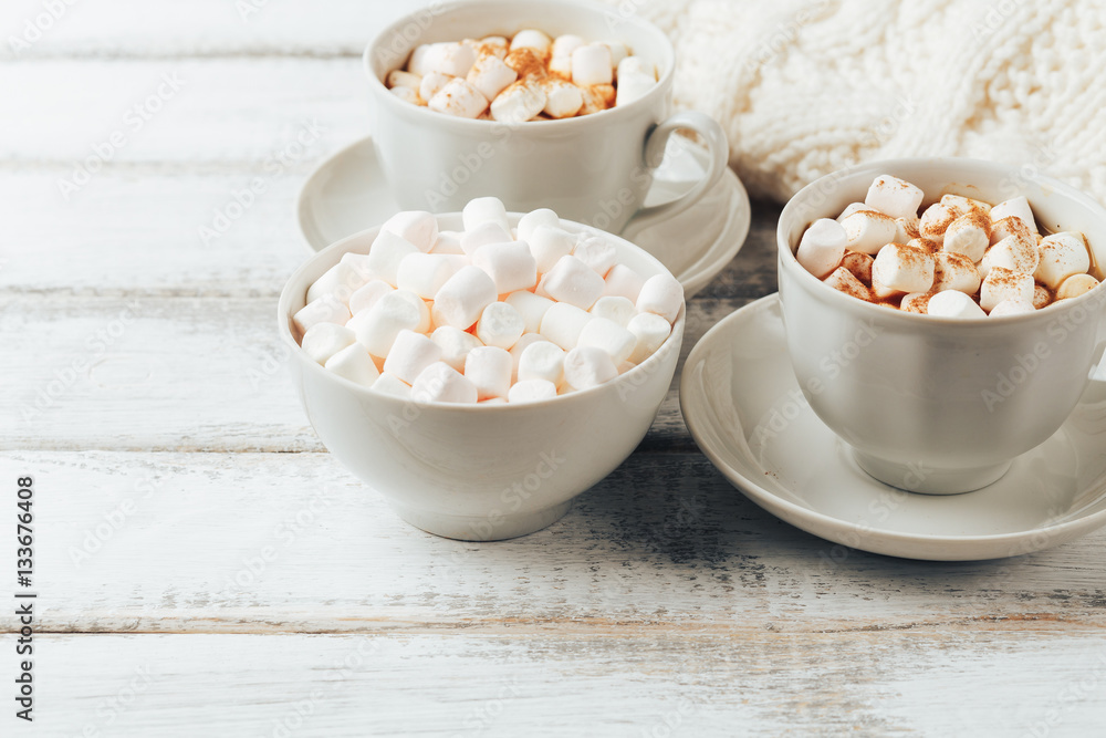 Cups with hot coffee or cocoa and marshmallows, white knitted blanked Cups with hot coffee or cocoa and marshmallows, white knitted blanked