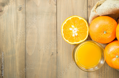 orange juice in glass and sliced orange in gunny sack on wood table top with copy space, top view