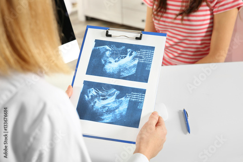 Doctor showing baby ultrasound image to pregnant woman photo