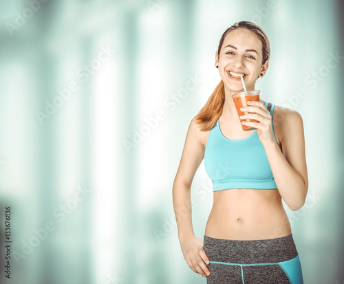 Young woman smiling and drinking fresh healthy smoothie after workout. Fitness and healthy lifestyle concept. photo