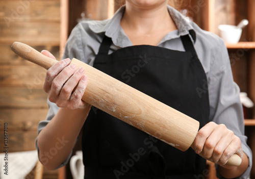 Young woman with roller pin in kitchen, closeup