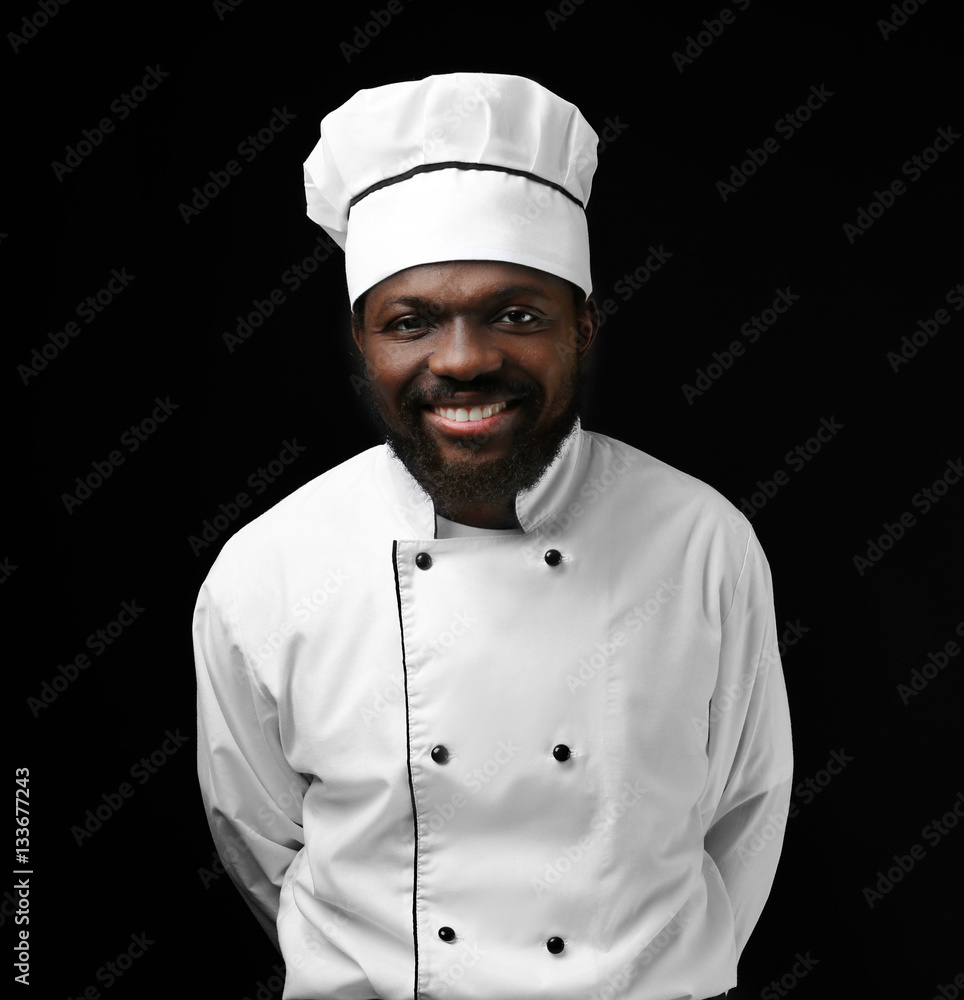 African American chef in uniform on dark background African American chef in uniform on dark background