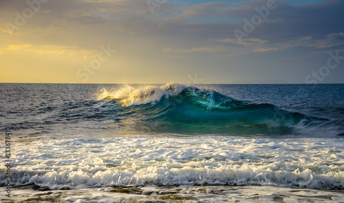 Big wave at sunset, with yellow light.