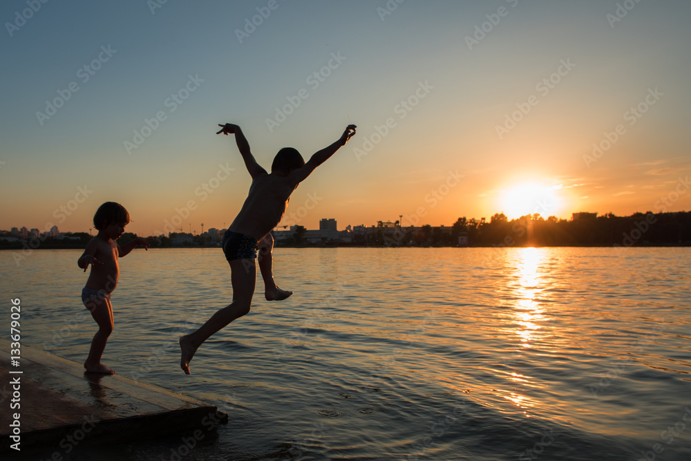 Boy jumping into the water. Sunset. Silhouette frame