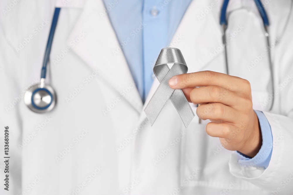 Doctor holding grey ribbon, close up view. Brain cancer, diabetes, asthma concept Doctor holding grey ribbon, close up view. Brain cancer, diabetes, asthma concept