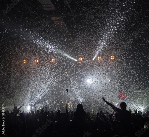 People enjoying good music at rock-concert. Falling of silvery confetti