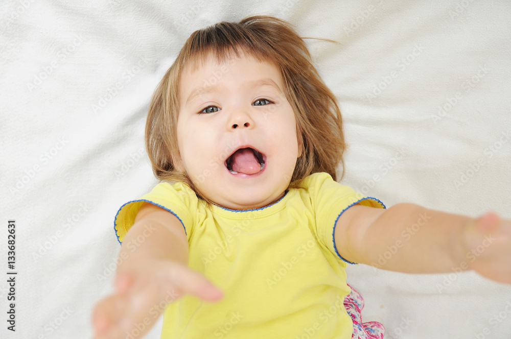 happy funny little girl with hands up lying on bed happy funny little girl with hands up lying on bed