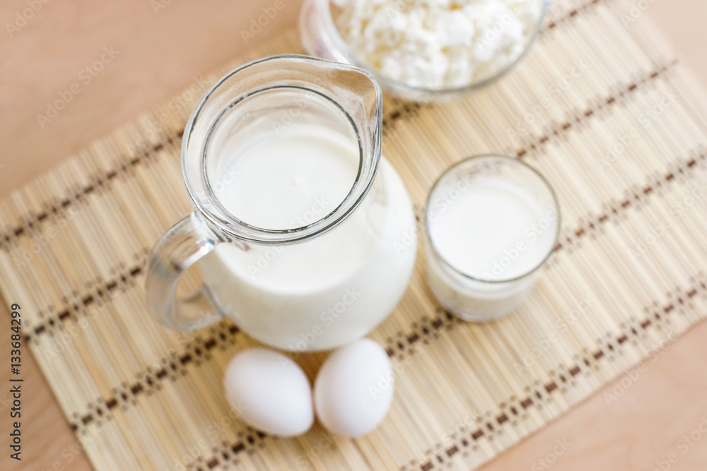Fresh milk in glass jug and glass, eggs, cottage cheese on wood table background, country rustic still life. Dairy products. Vintage Tone. Top view. Fresh milk in glass jug and glass, eggs, cottage cheese on wood table background, country rustic still life. Dairy products. Vintage Tone. Top view.