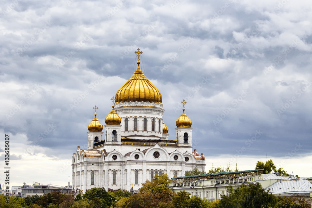Cathedral of Christ the Saviour under dramatic clouds in Moscow. Gleaming domes top this Catholic edifice, rebuilt in the 1990s, with ornate, fresco-lined interior.