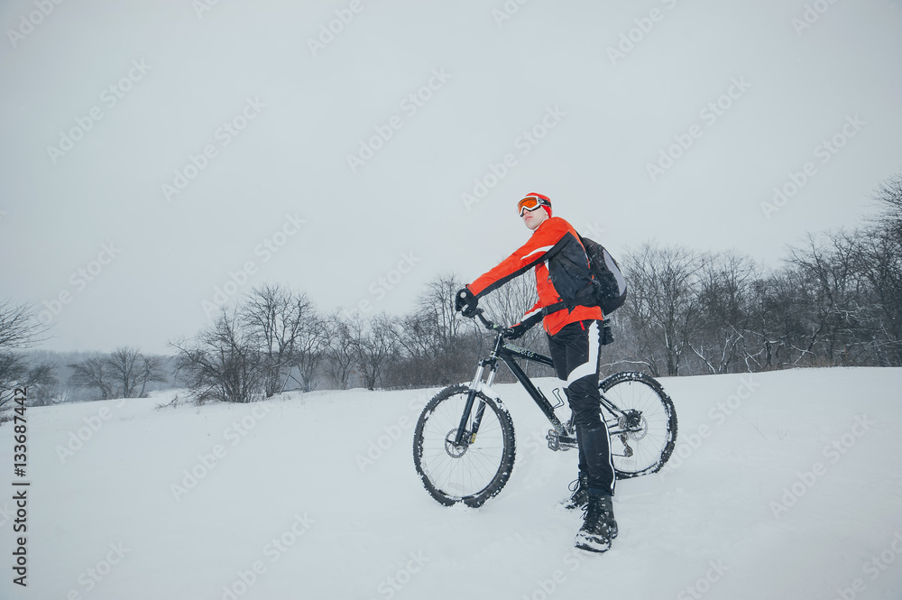 cyclist in red in the winter snowy forest