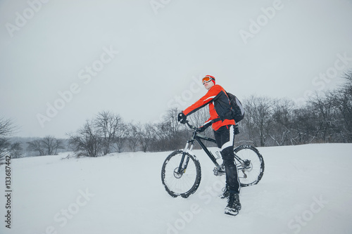 cyclist in red in the winter snowy forest © Dmitriy Shipilov
