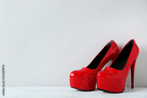 Pair of red women's high-heeled shoes on wooden table