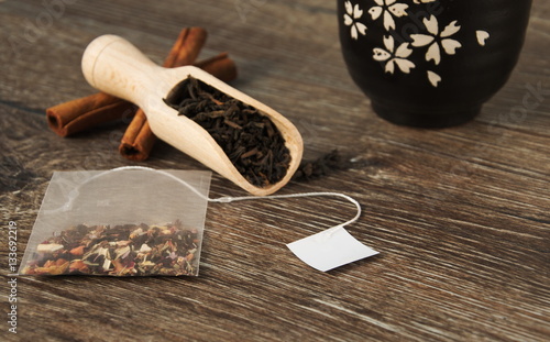 Tea bag in the background with a scoop of leaf tea and bowl for tea