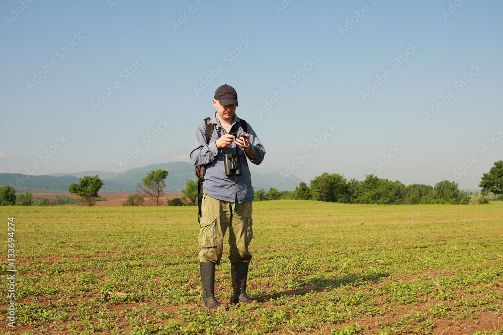 A young man is using GPS tracker on field background, sunny and blue sky A young man is using GPS tracker on field background, sunny and blue sky