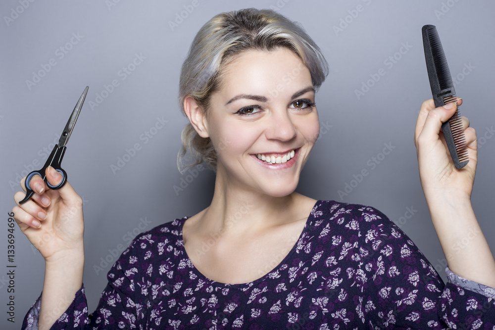 Young female hairdresser with scissors and comb advertising for a cosmetology school or a salon