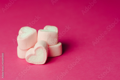 Marshmallows in heart shapes for Valentines day over pink paper