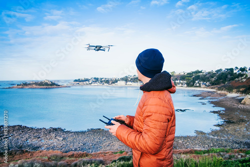 Drohnenpilot am Meer/Mann steuert eine Drohne an der Küste