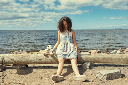lonley woman on the beach with his teddy bear 