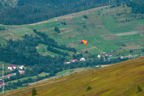 View of a tandem paraglider above the mountain valley.