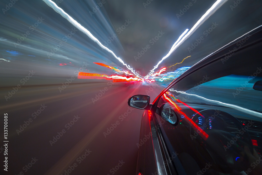 Obraz premium View from Side of Car moving in a night city, Blured road with lights with car on high speed. Concept rapid rhythm of a modern city.