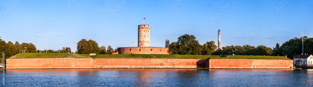 Medieval Wisloujscie Fortress with old lighthouse tower in port of Gdansk, Poland. A unique monument of the fortification works. Wide panorama in sunset light.