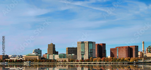 Photo of a cityscape of Boston across a river with reflections of buildings.