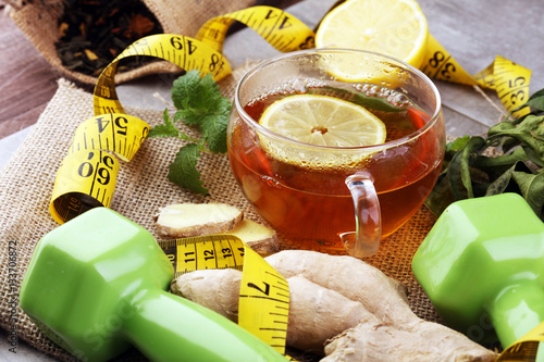 ginger tea - fitness liefestyle concept with tea, dumbells and measure tape - Healthy  tea detox photo