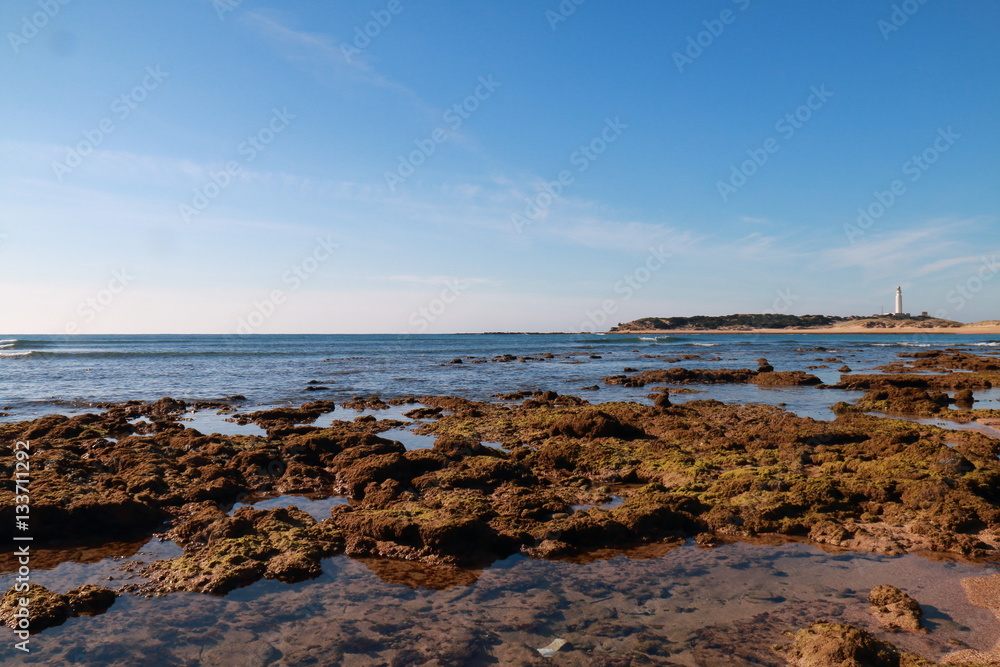 Beach of the Caños de Meca, with the lighthouse of Trafalgar in the background, in the cape of the same name, in the south of Spain Beach of the Caños de Meca, with the lighthouse of Trafalgar in the background, in the cape of the same name, in the south of Spain