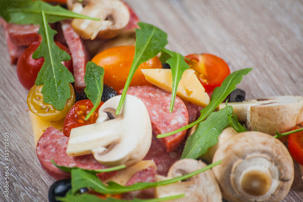 Creative composition of ingredients tomatoes, cheese, salami, mushrooms, arugula, olives in the form of a slice of pizza