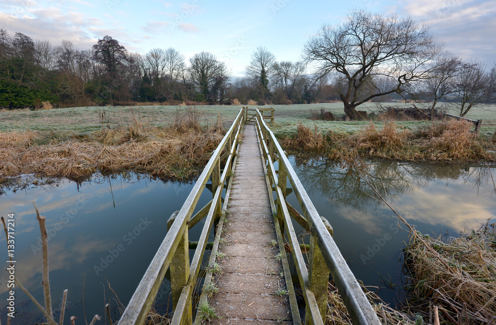 Wooden footbridge over a small river in winter