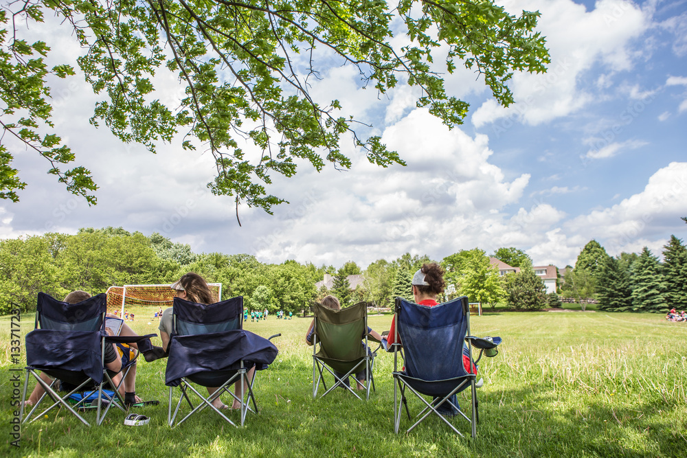 Naklejka premium Parents sitting watching a childrens soccer game