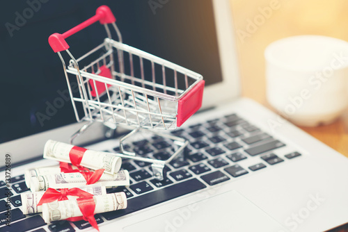 Tablet with money and shopping cart coffee on wooden table , online shopping concept