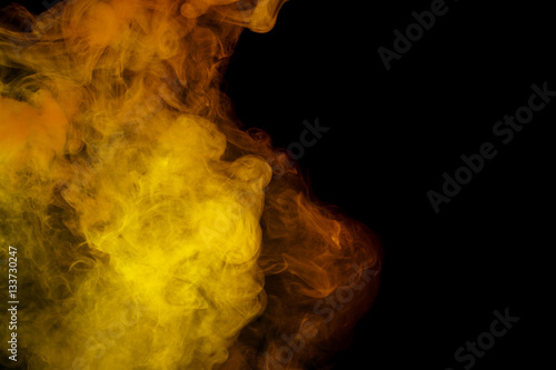 Abstract smoke Weipa. Personal vaporizers fragrant steam. The concept of alternative non-nicotine smoking. Yellow smoke on a black background. E-cigarette. Evaporator. Taking Close-up. Vaping.