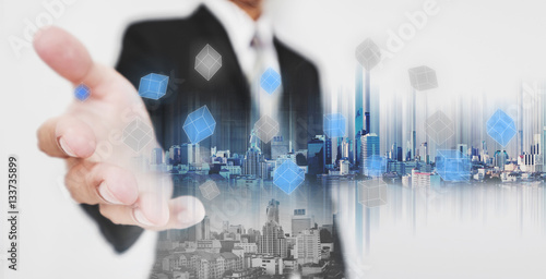 Double exposure businessman stretch out hand with modern buildings and pixel cubes, business network technology