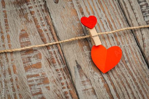 Red paper heart hanging on wood background .