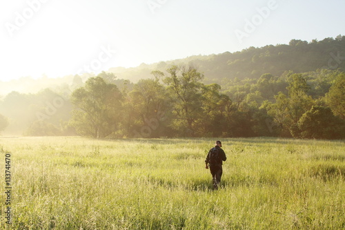 A man is hiking on grass field background early morning, sunny and blue sky