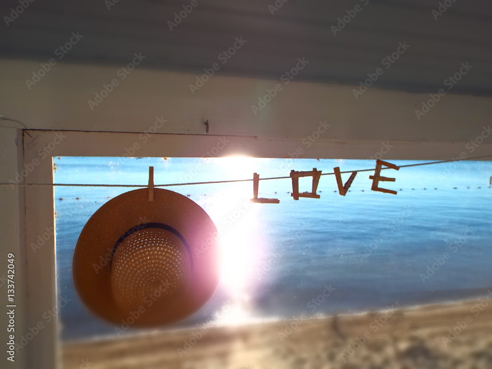 straw hat and word love spelled out in clothespins at lake house