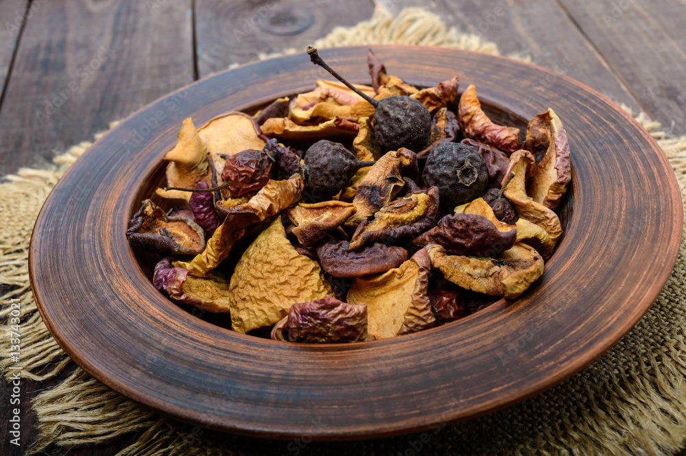 Dried fruit (apples, pears, apricots), berries in a bowl on dark wooden background. Close up. Ingredients for the winter vitamin drink, compote.
