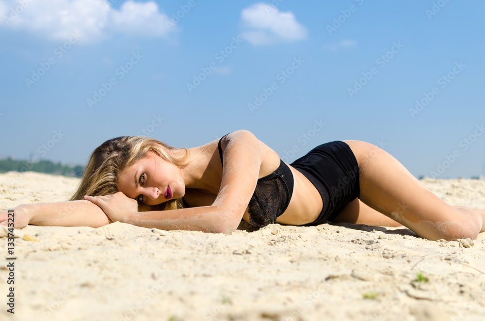 Luxury blond in black lingerie lying on a sandy beach Luxury blond in black lingerie lying on a sandy beach