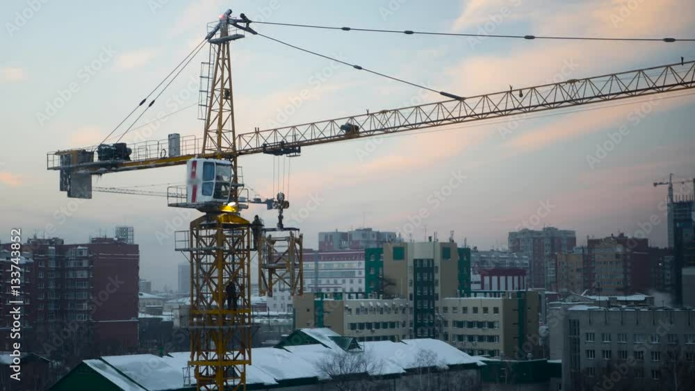 workers at a construction site collect construction crane at sunset, 4k workers at a construction site collect construction crane at sunset, 4k