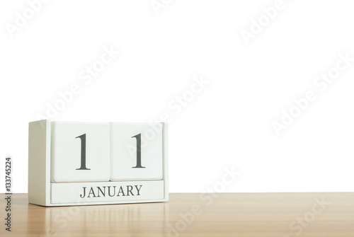 Closeup surface white wooden calendar with black 11 january word on blurred brown wood desk isolated on white background with copy space   selective focus at the calendar