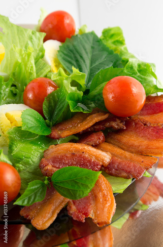 Plate of fried bacon, cherry tomatoes and herbs