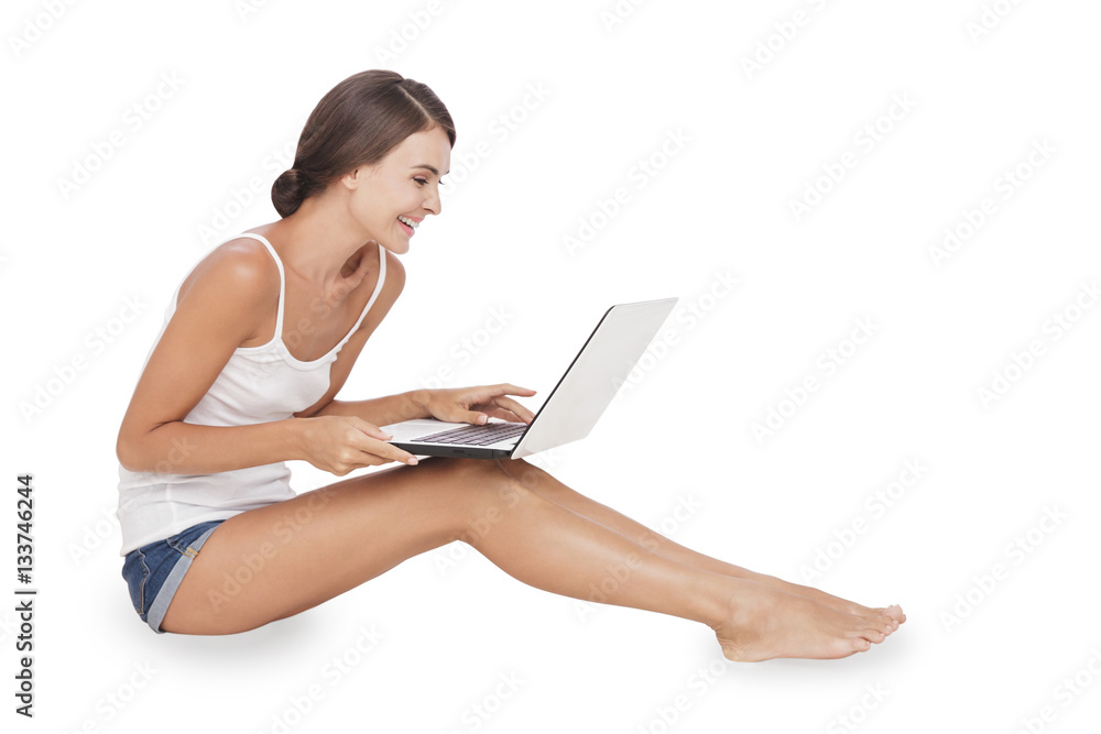 young woman sitting on the floor while working on her laptop young woman sitting on the floor while working on her laptop