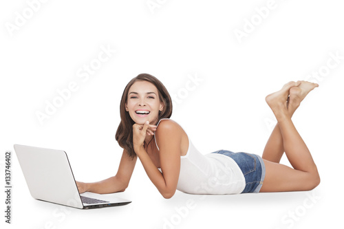 young woman smiling and enjoy playing on her laptop