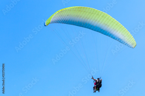 Paragliding in blue sky, instructor and beginner