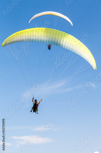 Amateur paragliders in blue sky with clouds