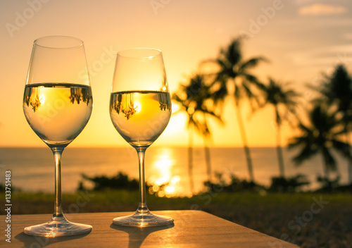 Romantic getaway  and dinning concept. Pair of wine glasses against a beautiful beach sunset. 