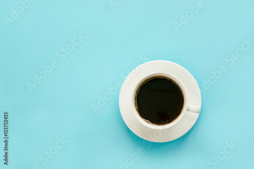 Cup of black coffee with milk on blue background. Isolated. Top view.